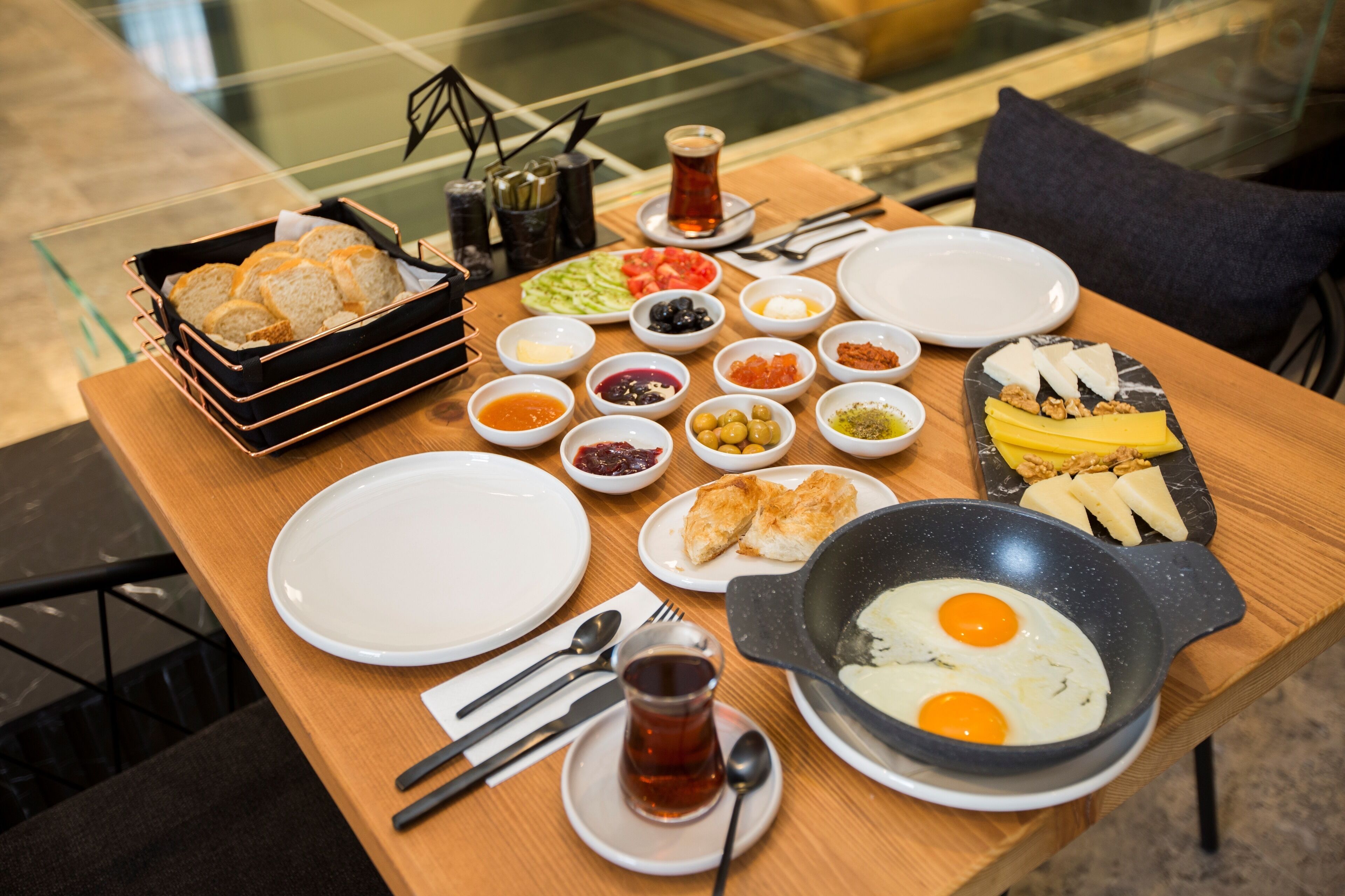 Una mesa de desayuno con diversos platos, como huevos, pan y salsas.