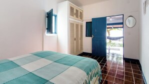 Ein Schlafzimmer mit Bett, Kleiderschrank, einer Tür zum Außenbereich und einem Fenster.