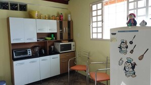 Eine kleine Küche mit weißen Schränken, einer Mikrowelle, einem Toaster und einem Kühlschrank mit Kinderbildern.