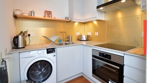 A compact kitchen with a washing machine, oven, and a microwave.