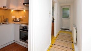A modern kitchen with white cabinets, stainless steel appliances, and a yellow striped rug leading to a door.