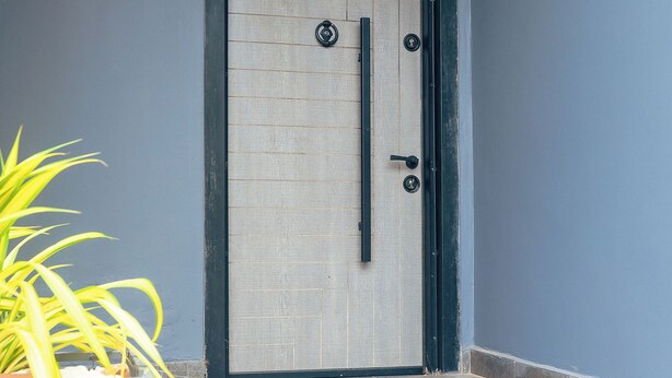 A door with a black frame, a vertical handle, and two round keys.
