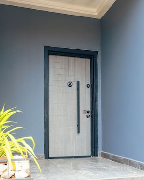 A door with a black frame, a vertical handle, and two round keys. - Experience luxury living at Tower Properties.  (Accra)