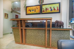 A reception desk with patterned panels, a clock, and two framed artworks above it.