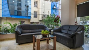 A modern lobby with two leather sofas, a glass coffee table, and potted plants. - HOTEL THE GRAND TARA (Indore)