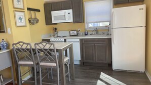 Une cuisine compacte avec un coin repas, comprenant un four à micro-ondes, une cuisinière, un évier et un réfrigérateur.