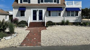Une maison à deux étages avec un porche à l’avant, une adresse bien visible et une allée gravillonnée.