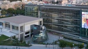 Un edificio moderno con facciata in vetro, un grande cartellone pubblicitario e un parcheggio.