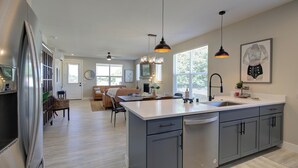 Una cocina moderna con una isla grande, electrodomésticos de acero inoxidable e iluminación colgante.