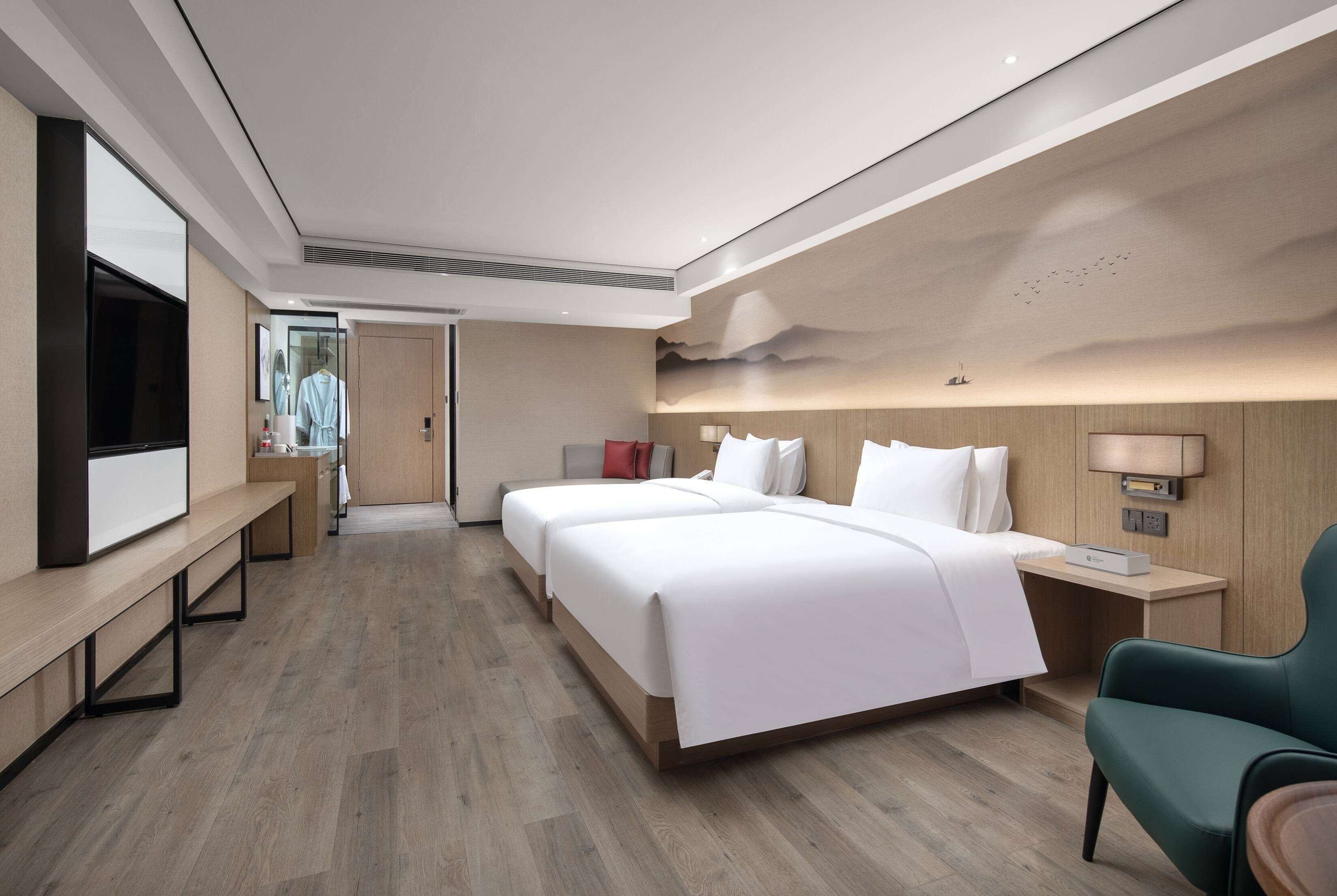 Una habitación de hotel moderna con una cama grande, mesitas de noche, un televisor y una zona de estar.