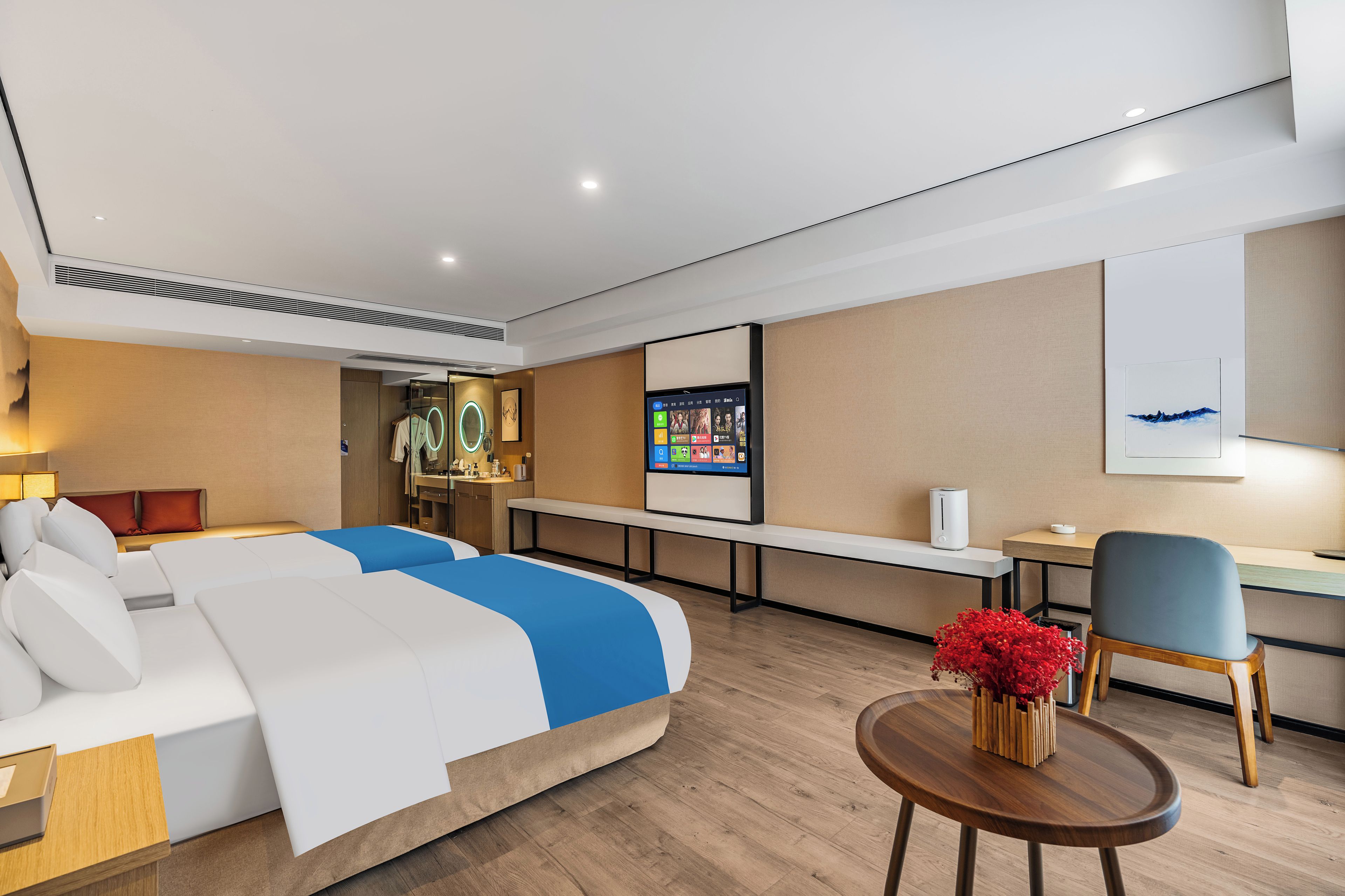 A modern hotel room with a large bed, a desk, a chair, a small table, and a TV.
