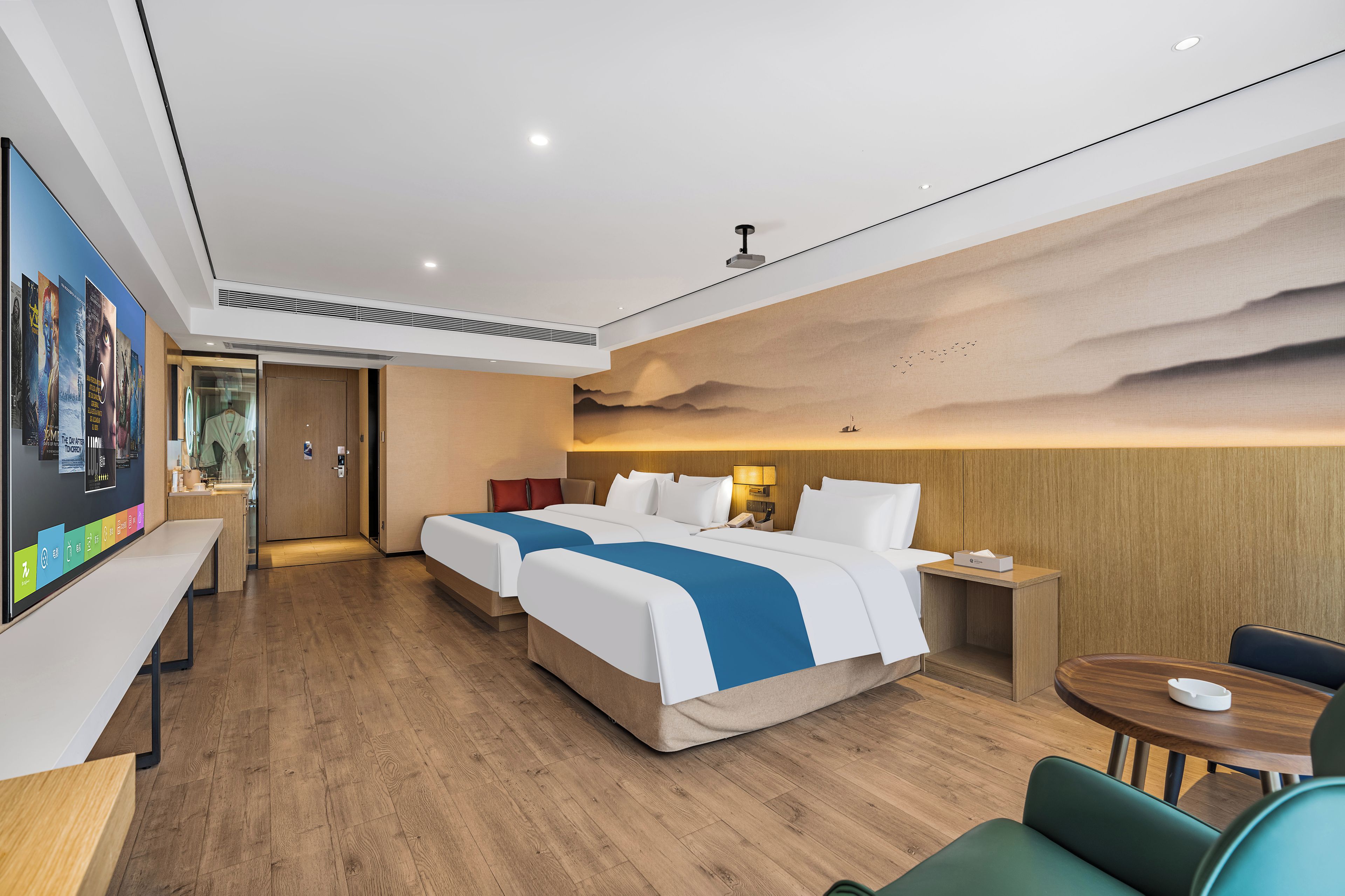 A hotel room with a large bed, a desk, a chair, and a wall with a movie poster.