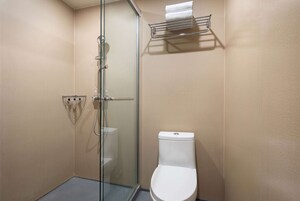 Un baño con cabina de ducha de vidrio, inodoro blanco y un perchero para toallas.