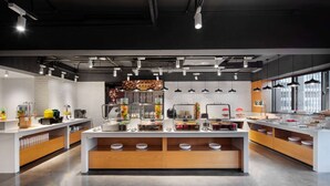 A modern kitchen with white countertops, wooden cabinets, and a central island with bowls. - Ramada Encore by Wyndham Kunming Guandu (Kunming)