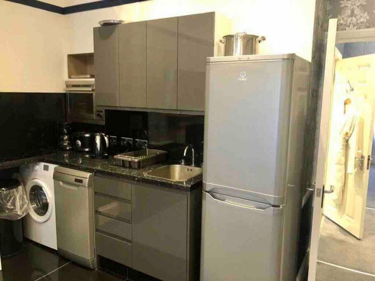 A compact kitchen with a washing machine, a refrigerator, and a microwave.