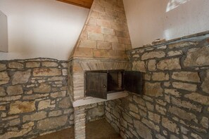 Ein Steinkamin mit Schornstein, der in eine Hausecke mit Steinwänden integriert ist.