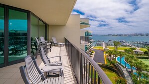 A balcony with chairs, a pool, and a marina view.