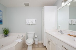 Un baño moderno con bañera, inodoro, lavabo y un espejo grande.