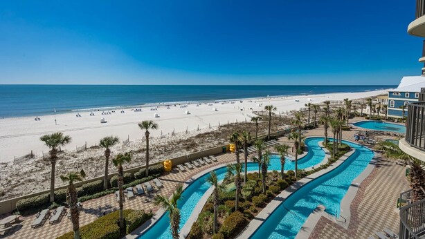 Un resort con vista a la playa, varias piscinas y una zona de playa arenosa.