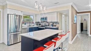 A modern kitchen with stainless steel appliances, a central island with bar seating, and a view to the outdoors. - 49th Ave Gem in Lealman area (St. Petersburg)