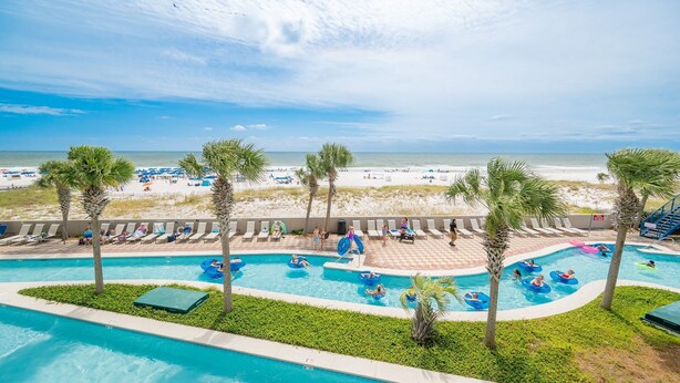A pool area with multiple swimming pools, lounge chairs, and palm trees.