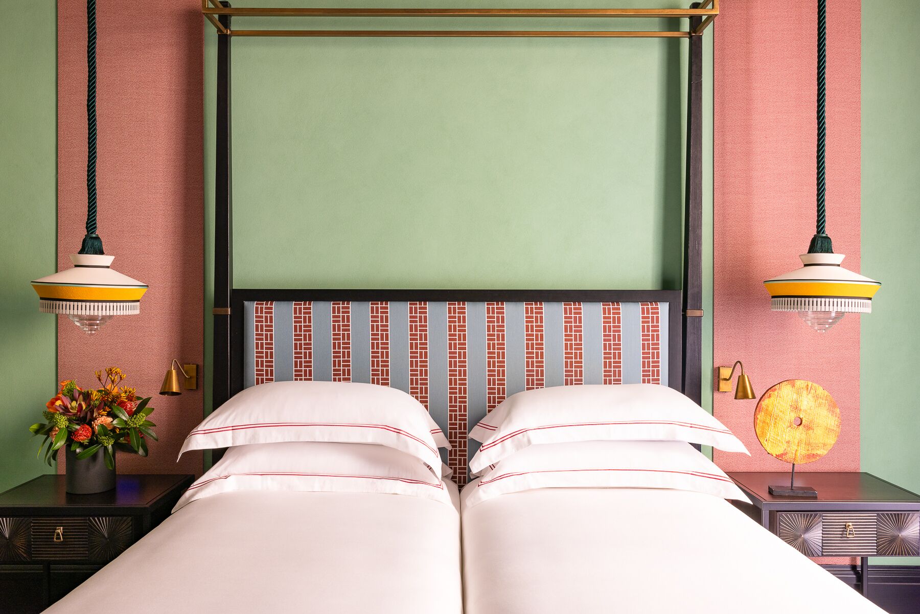 A double bed with a headboard featuring a brick pattern, flanked by two nightstands with lamps.