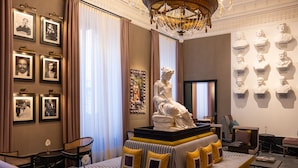 A room with a central seating area, framed pictures on the walls, and busts on the right. - Palazzo Roma - The Leading Hotels of the World (Rome)