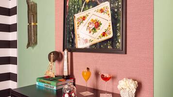 Una habitación con una pared verde, una obra de arte floral enmarcada, un libro titulado 'Flower Men', un frasco de vidrio con bayas y un jarrón decorativo.