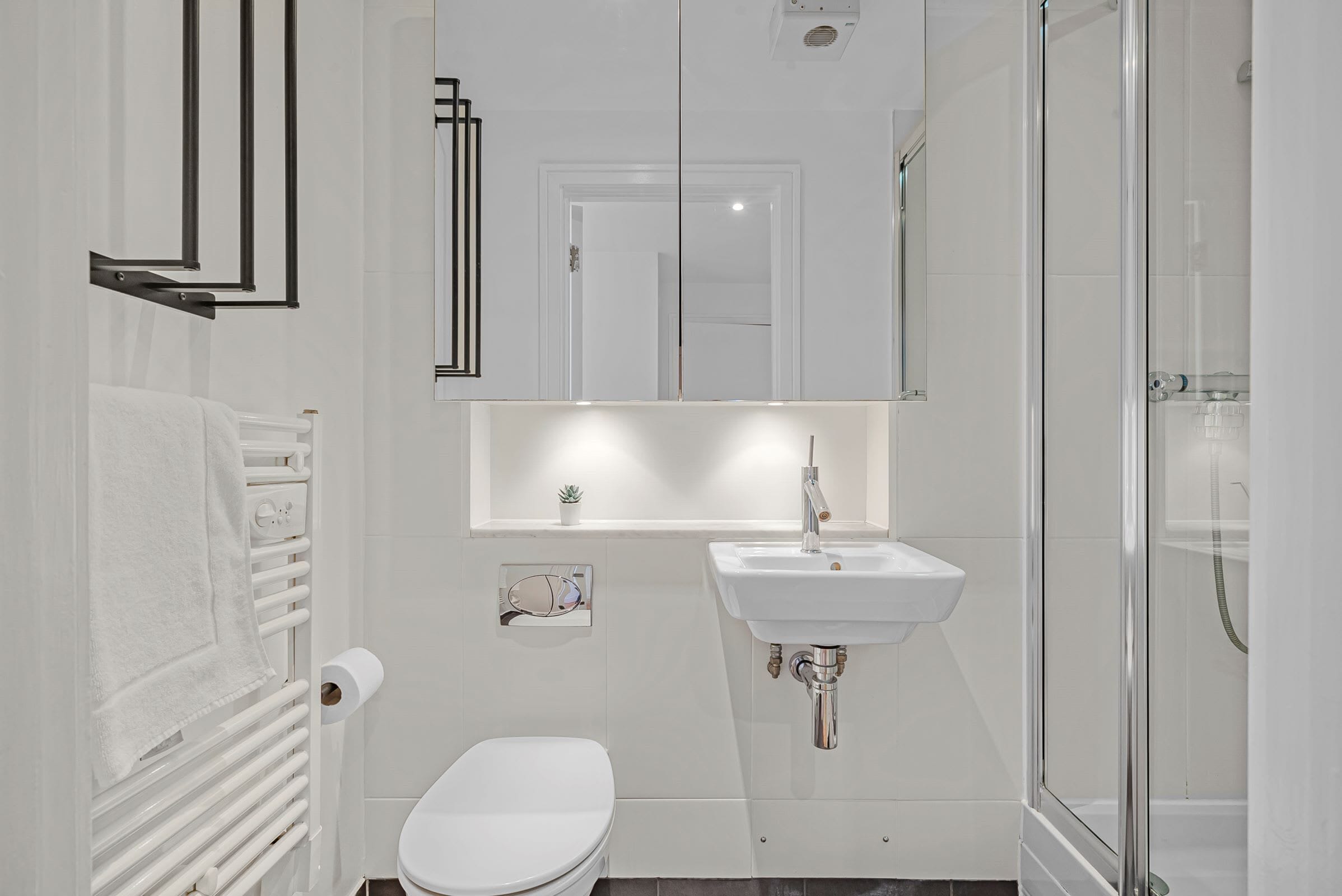 Een moderne badkamer met een wit toilet, een wastafel en een douchecabine met glazen wanden.