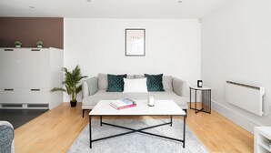 A modern living room with a sofa, coffee table, and a potted plant. - Spacious 2BR with Terrace by King's Cross (London)