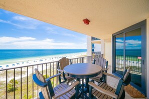 Un balcon avec une table et des chaises donnant sur une plage.