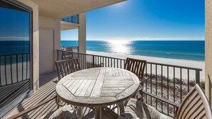 A wooden table and chairs on a balcony with a view of the ocean. - Phoenix X 805 1 Bedroom Condo (Orange Beach)
