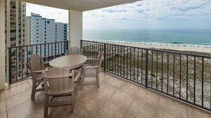 A balcony with a view of the beach, a table, and chairs. - Phoenix Vii 71016 2 Bedroom Condo (Orange Beach)