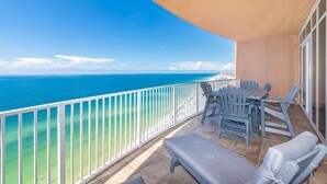 A balcony with a view of the ocean, a table with chairs, and a lounge chair. - Phoenix Orange Beach 2106 4 Bedroom Condo (Orange Beach)