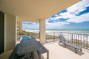Varanda com vista para a praia, piscina e espreguiçadeiras.