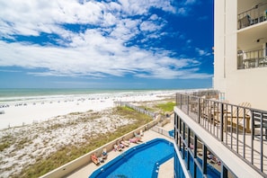 Un hotel con piscina, vistas a la playa y un balcón con tumbonas.