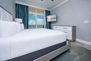 A bedroom with a bed, a dresser, a TV, and a window with curtains. - Phoenix Gulf Shores 1102 3 Bedroom Condo (Gulf Shores)