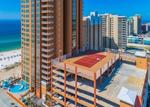 A high-rise hotel with multiple floors, a rooftop tennis court, and a pool area with a water slide. - Phoenix Gulf Shores 1102 3 Bedroom Condo (Gulf Shores)