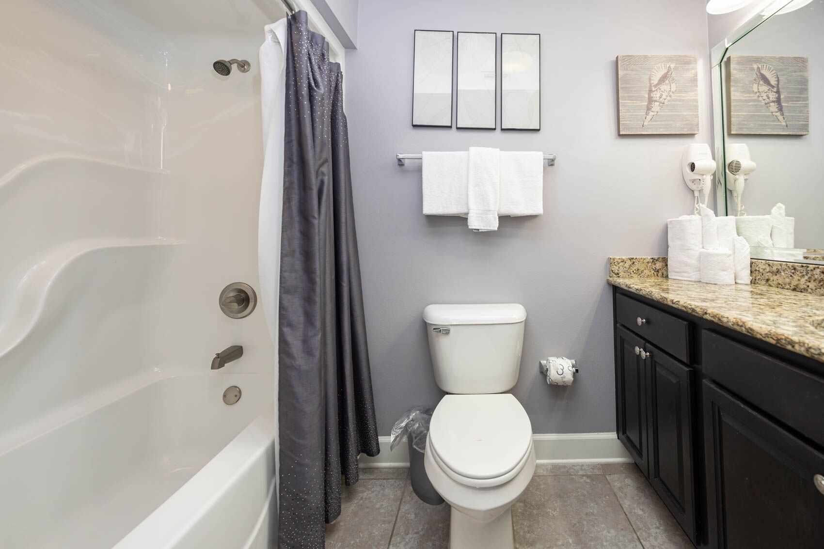 A bathroom with a bathtub, toilet, and vanity with a mirror.