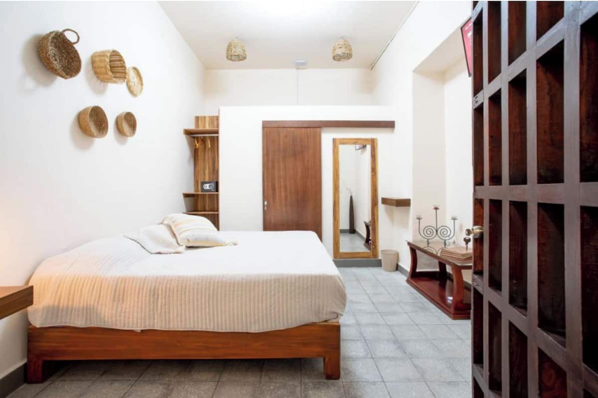 A bedroom with a wooden bed, a wardrobe, a mirror, and a small table with a candle.