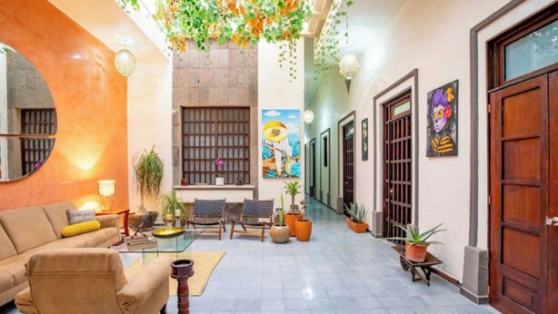 Eine großzügige Lobby mit einer Couch, Sesseln, einem Couchtisch und Zimmerpflanzen.