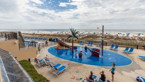 Een zwembad met glijbaan, ligbedden en uitzicht op het strand.