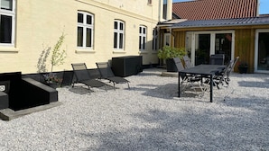 A building with a patio area featuring outdoor seating and a table. - Sejerø Vandrerhjem (Sejero)