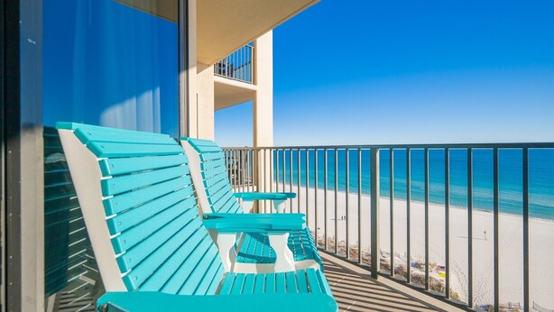 Un balcon avec des bancs turquoise donnant sur une plage.
