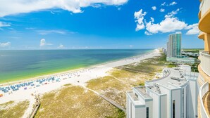 A beach view with a high-rise building, a sandy beach, and a clear blue sky. - Phoenix Orange Beach Ii 1603 2 Bedroom Condo (Orange Beach)