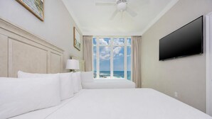 A hotel room with a large bed, a ceiling fan, a TV, and a view of the ocean. - Phoenix Orange Beach Ii 1905 4 Bedroom Condo (Orange Beach)