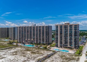 Experience the contemporary architecture and scenic views of this high-rise complex, featuring a central courtyard with a swimming pool and lush greenery.