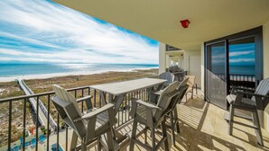 A balcony with a view of the beach and ocean, a table, and chairs. - Phoenix Vii 7508 3 Bedroom Condo (Orange Beach)