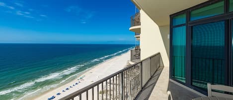 A balcony with a view of the beach and ocean.