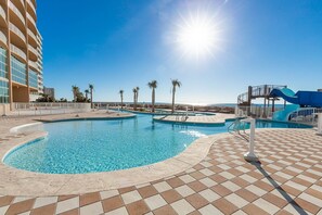 Relax by the pool surrounded by palm trees and a small slide for kids.